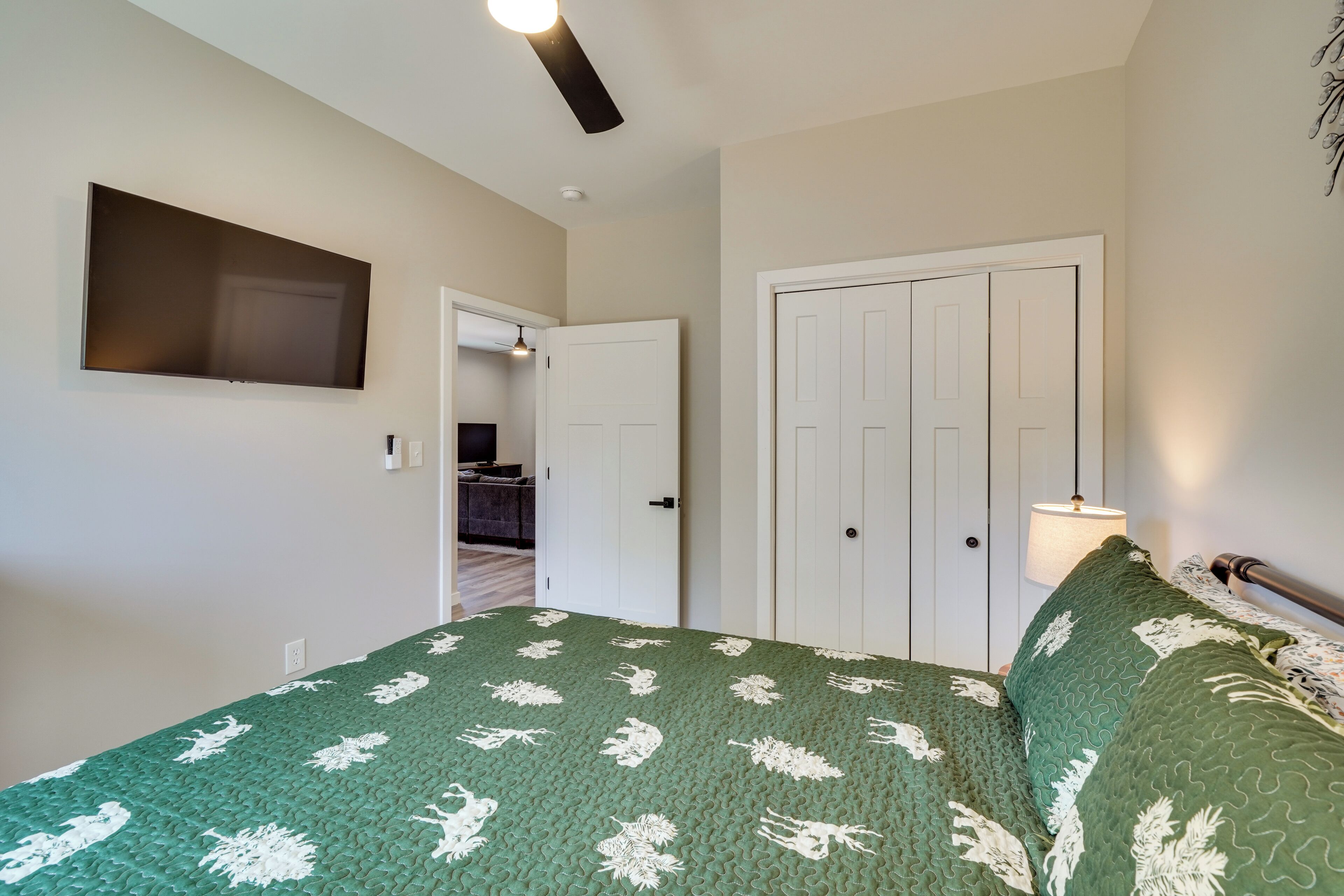 Un dormitorio con cama, televisor, puerta y lámpara.