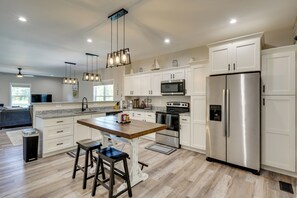 A modern kitchen with white cabinets, stainless steel appliances, a wooden island, and pendant lighting. - Cottage 1 Mi to Lake Gaston Beach & Boat Launch (Littleton)