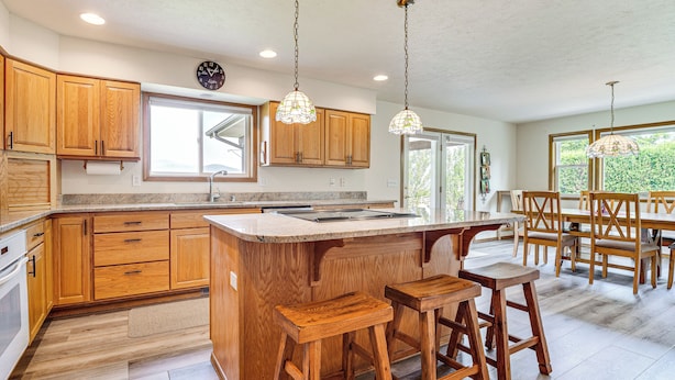A modern kitchen with wooden cabinets, a large island with stools, and pendant lighting. - Lake Roosevelt Retreat Lake: Mtn Views, Game Room (Davenport)