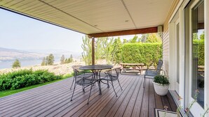 A covered outdoor patio with a table and chairs, overlooking a scenic landscape. - Lake Roosevelt Retreat Lake: Mtn Views, Game Room (Davenport)