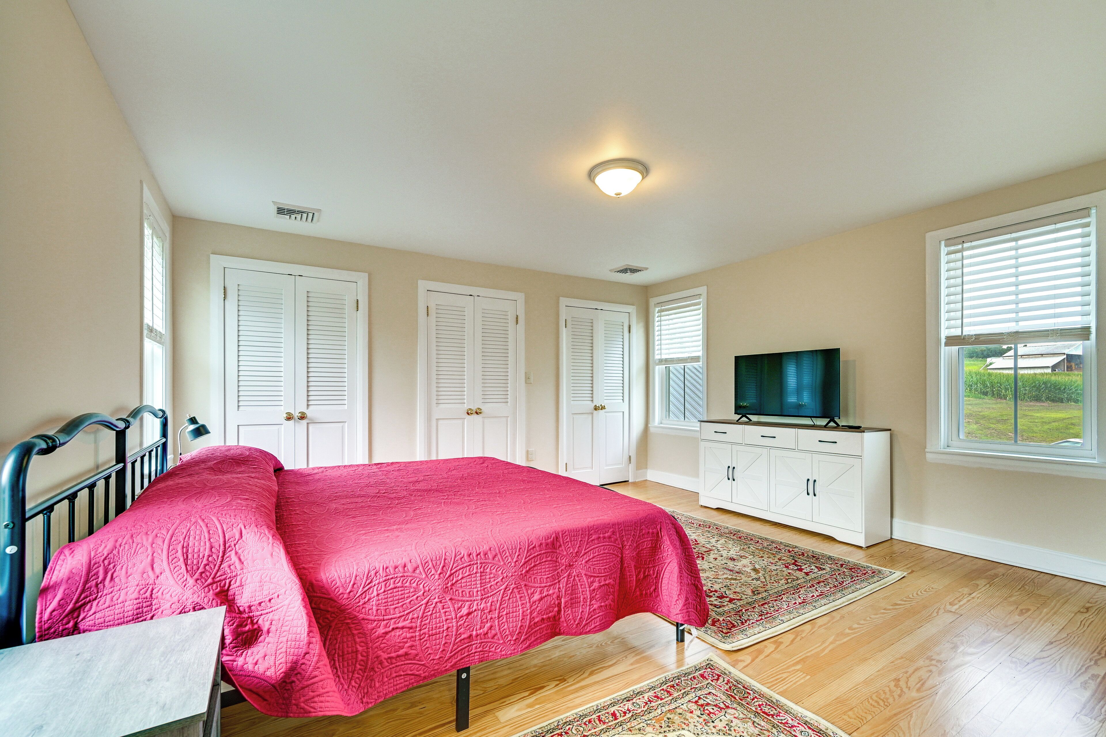 A bedroom with a bed, a television, a dresser, and a window with blinds.