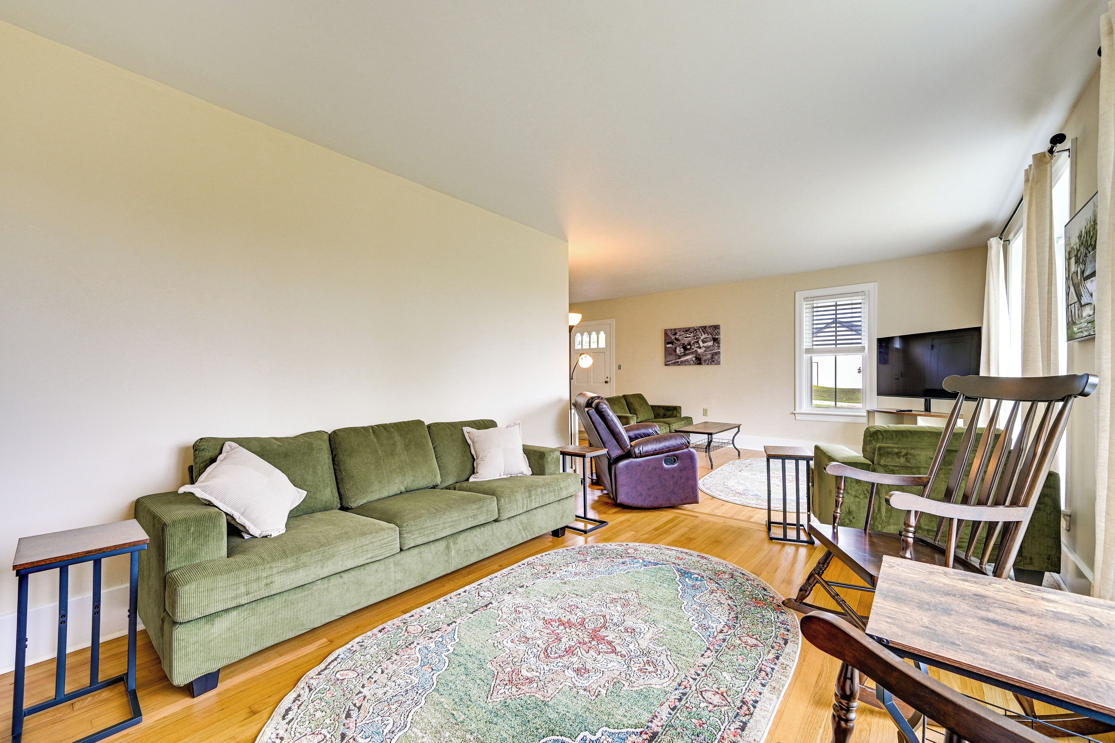 A living room with a green sofa, a recliner, a wooden coffee table, and a patterned rug.