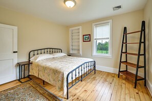 A bedroom with a bed, a wooden floor, a window with blinds, a ladder, and a door. - Farmhouse W/creek & Fireplace Near Gettysburg! (Biglerville)
