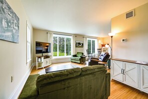 A living room with a green sofa, a television, and a large window. - Farmhouse W/creek & Fireplace Near Gettysburg! (Biglerville)