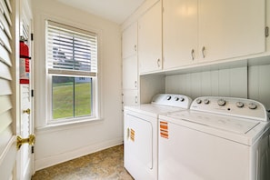 A laundry room with a washer and dryer, a window with blinds, and a door with a brass handle. - Farmhouse W/creek & Fireplace Near Gettysburg! (Biglerville)