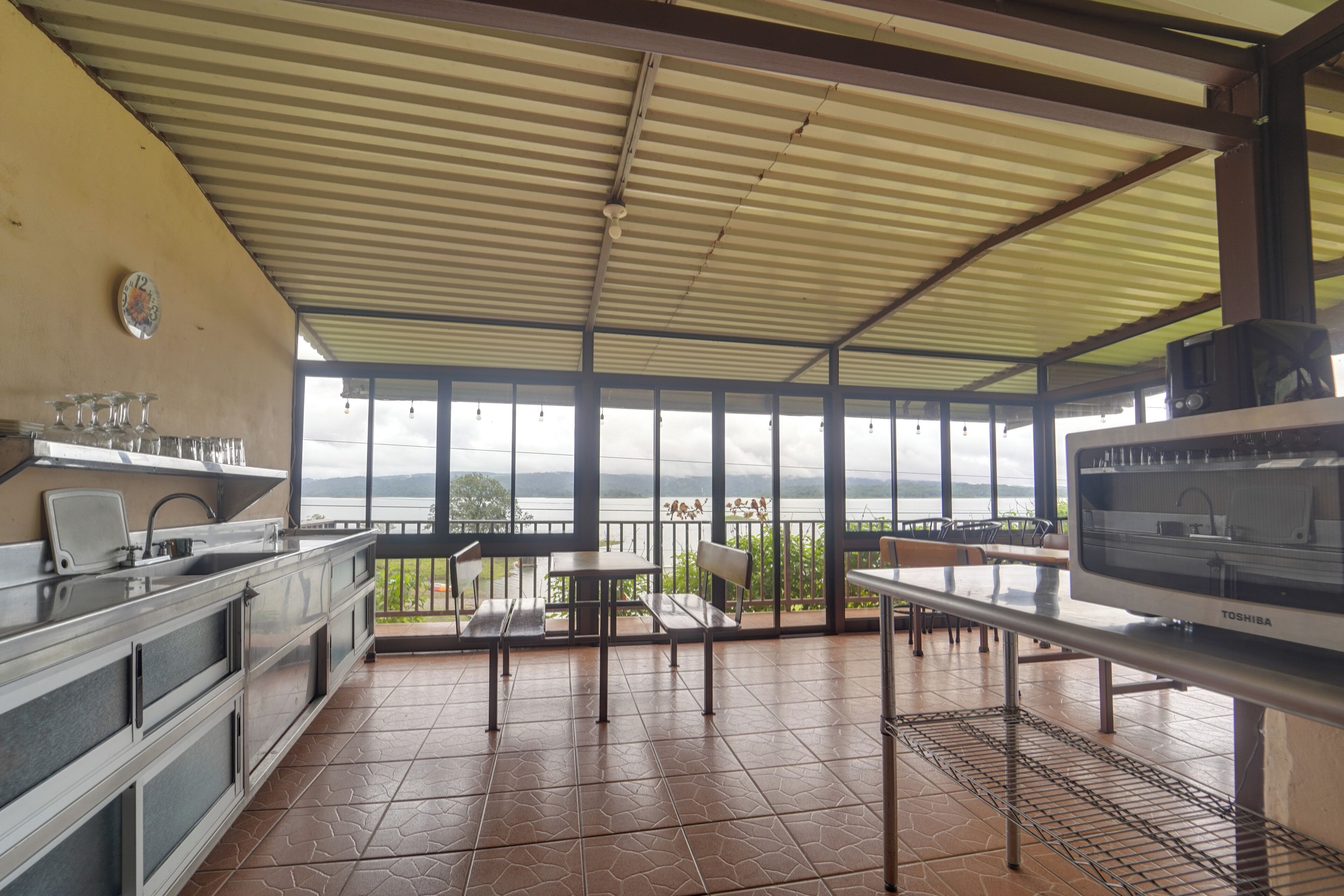 A kitchen with a view of a lake, a dining area with tables and chairs, and a large window.