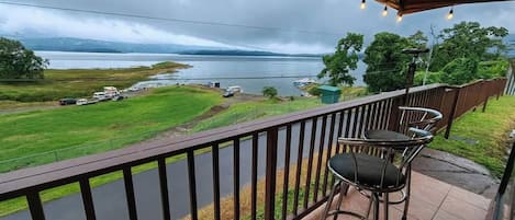 Ein Balkon mit Blick auf einen See, ein Stuhl und ein Tisch.