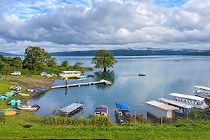 A lakeside view with boats, a dock, and a mountainous backdrop.
