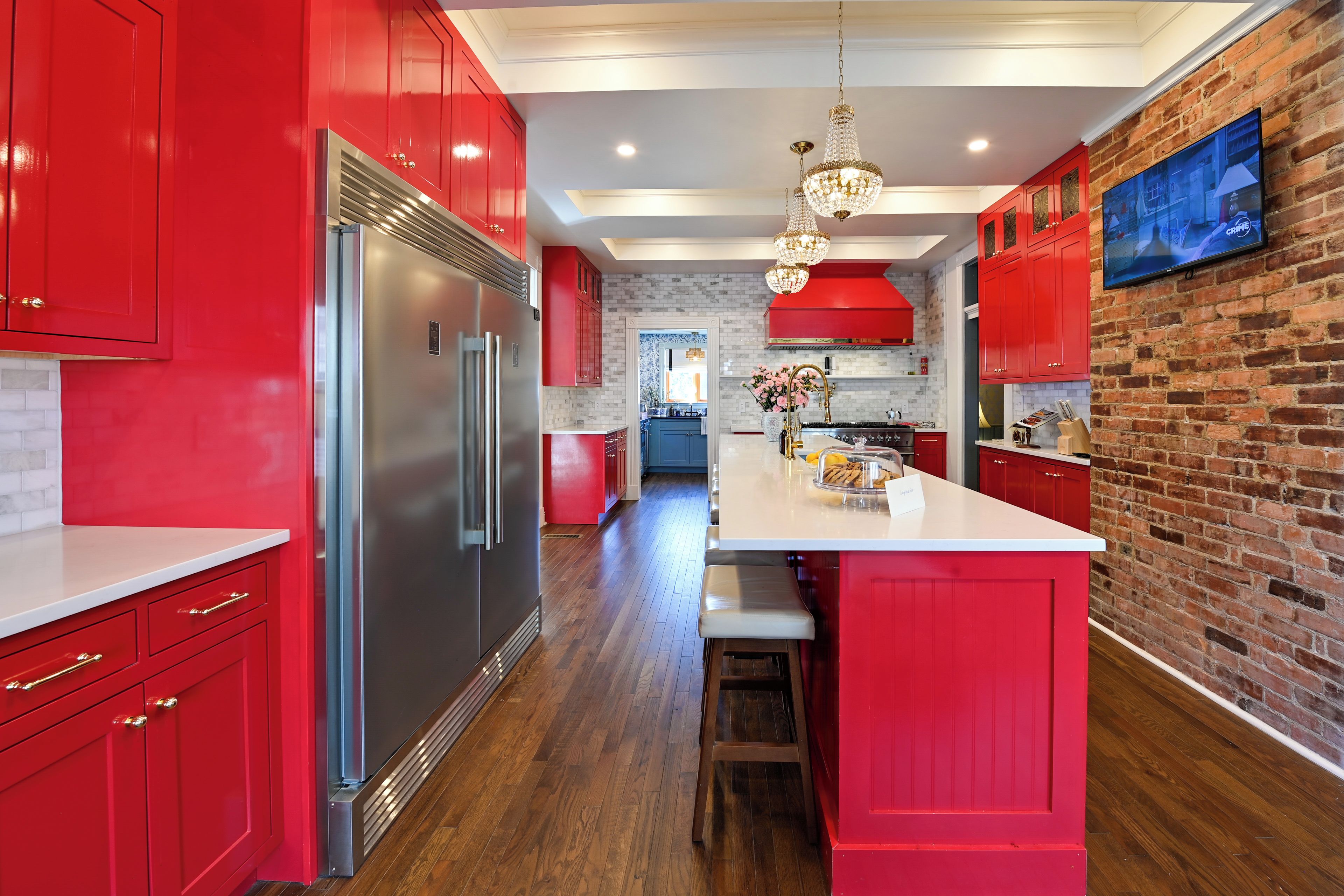 A modern kitchen with red cabinetry, stainless steel appliances, and a central island.