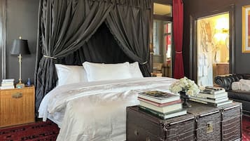 Un dormitorio con cama, mesita de noche, cómoda y cortina roja.