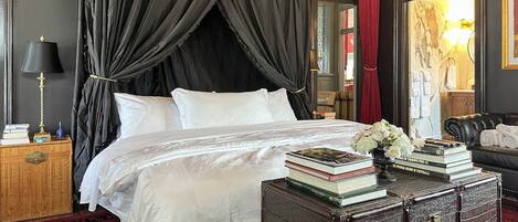 Un dormitorio con cama, mesita de noche, cómoda y cortina roja.