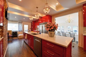 Una cocina moderna con armarios rojos, una isla central y un comedor con vistas.