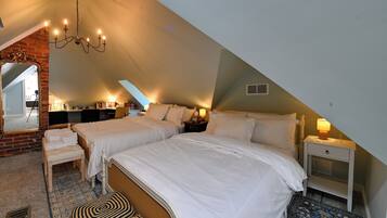 A cozy attic bedroom with two beds, a chandelier, and a large mirror.