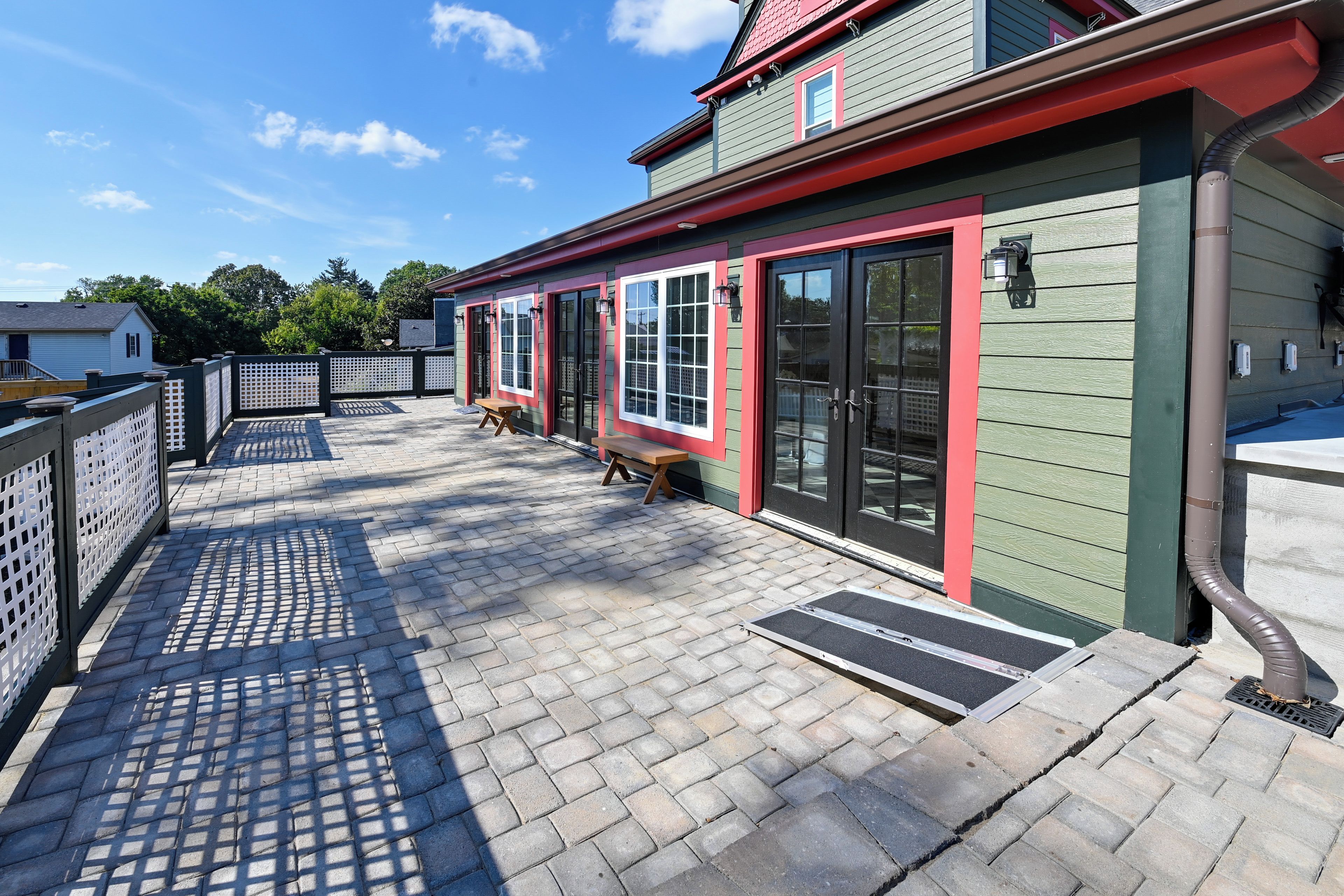 A building with a red and green exterior, a paved patio with a bench, and a clear sky.