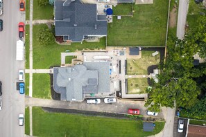 An aerial view of a residential area with multiple houses, a driveway, and parked cars.