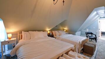 A bedroom with two beds, a chandelier, a chair, and a small table with a lamp.