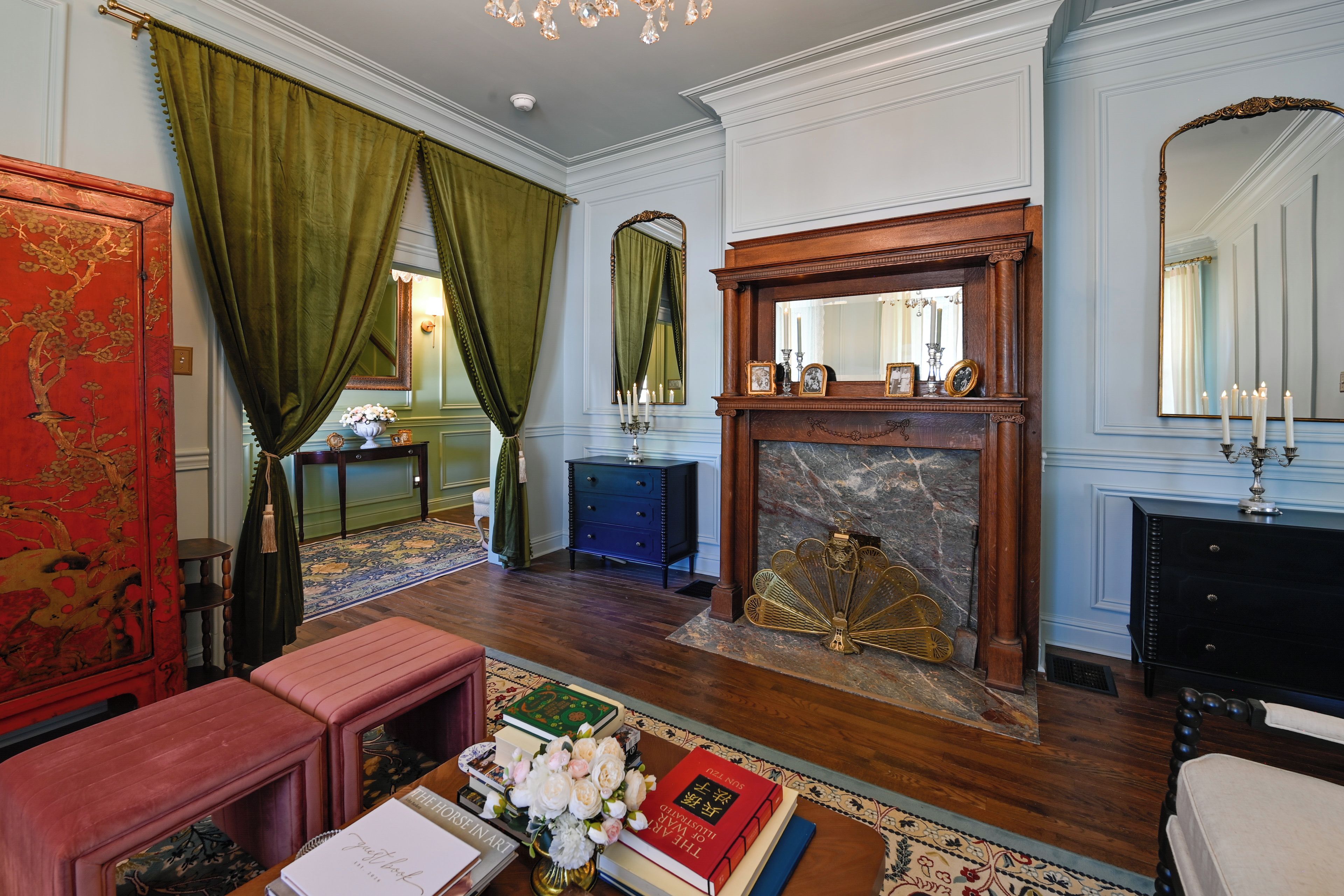 A traditional room with a fireplace, a mirror, and a red cabinet.