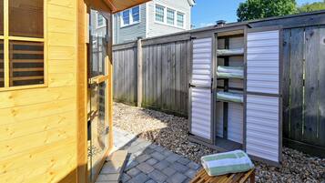 A wooden cabin with a small patio area, a wooden deck, and a shed with sliding doors.