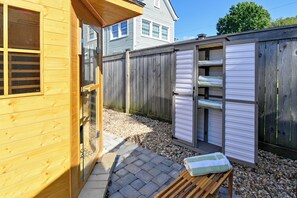 Una cabaña de madera con un pequeño patio, una terraza de madera y un cobertizo con puertas correderas.