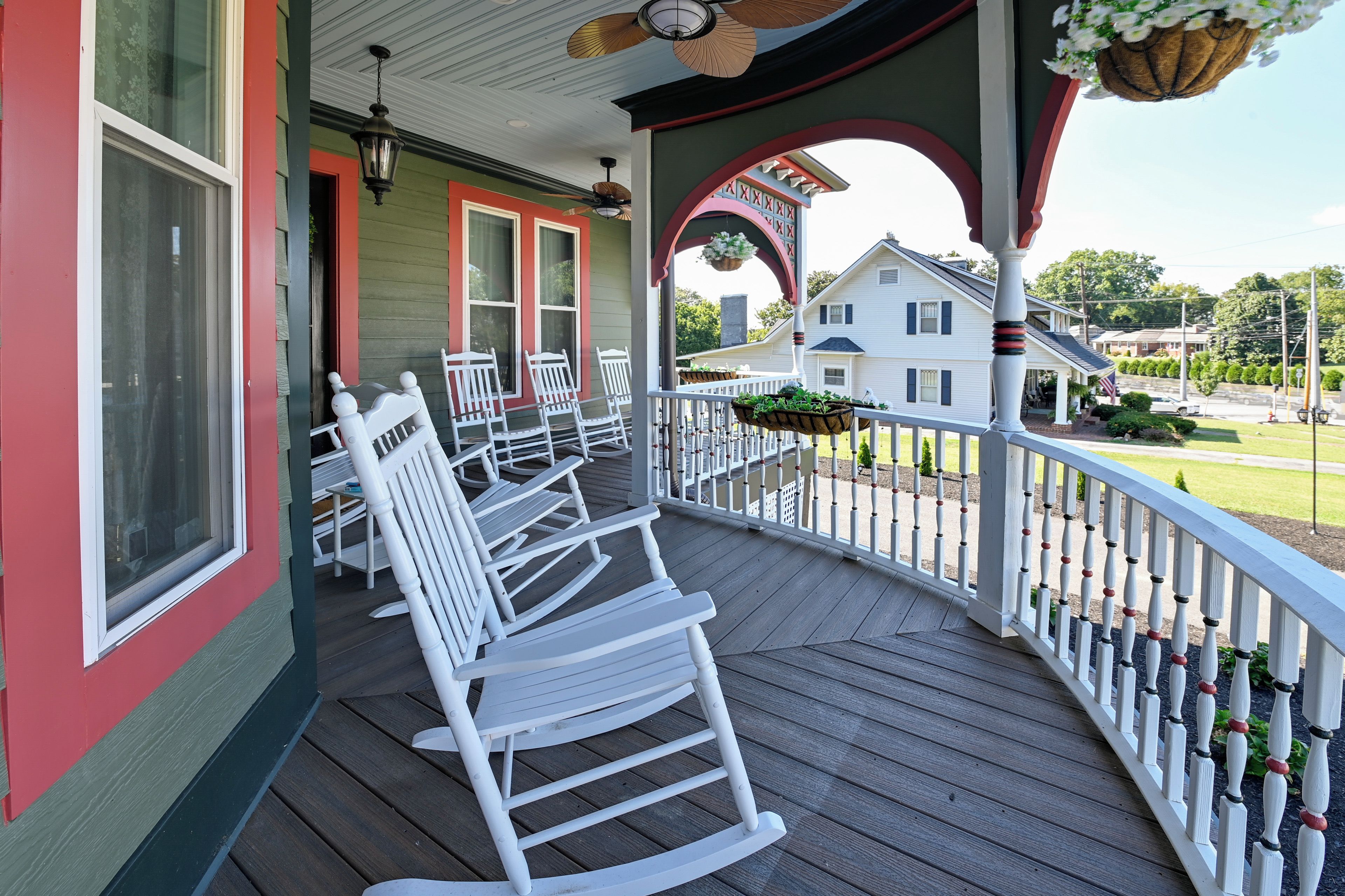 Une véranda avec des fauteuils à bascule blancs et, au loin, une maison blanche.