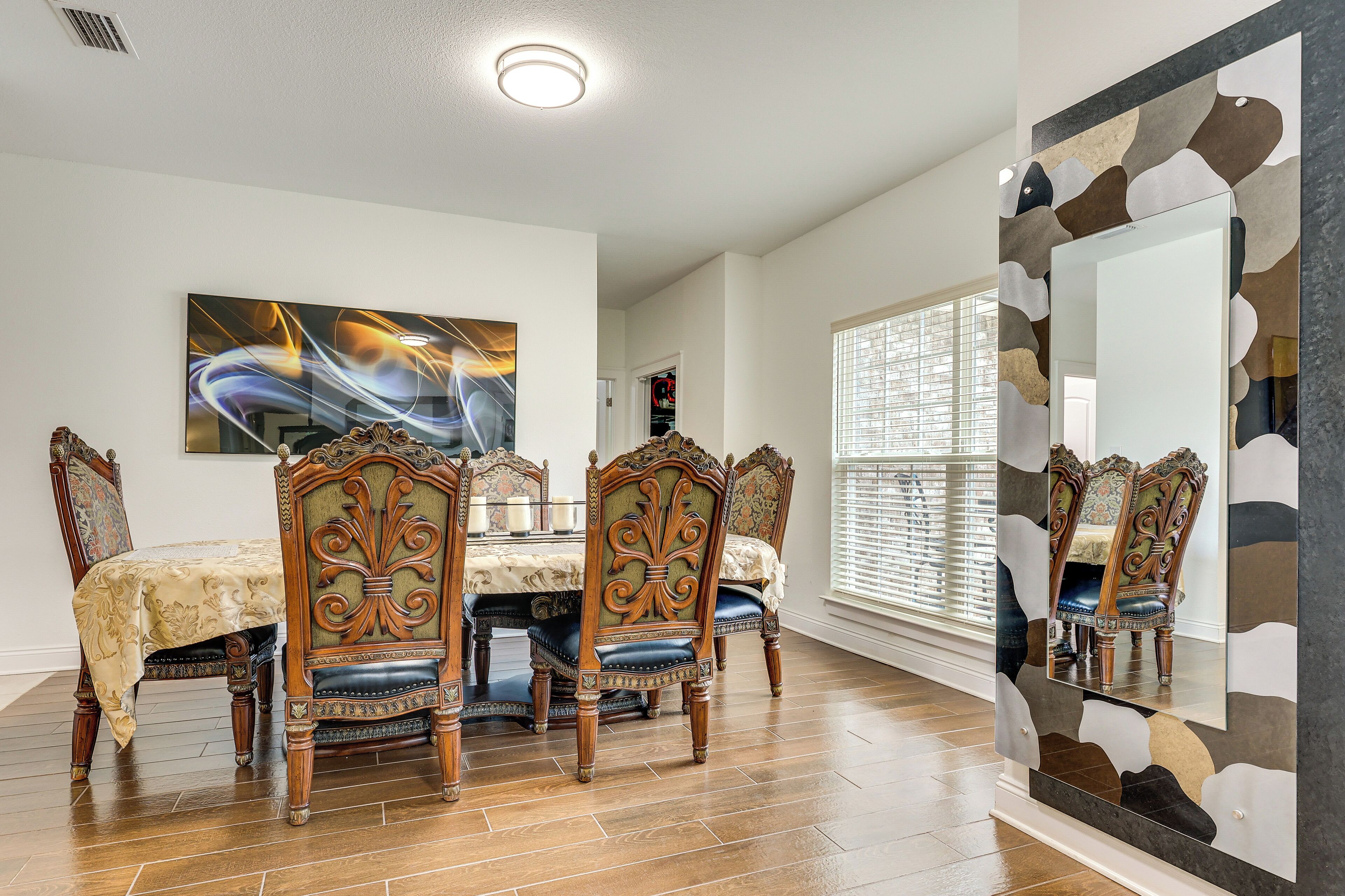 A dining room with a table, chairs, and a large mirror.