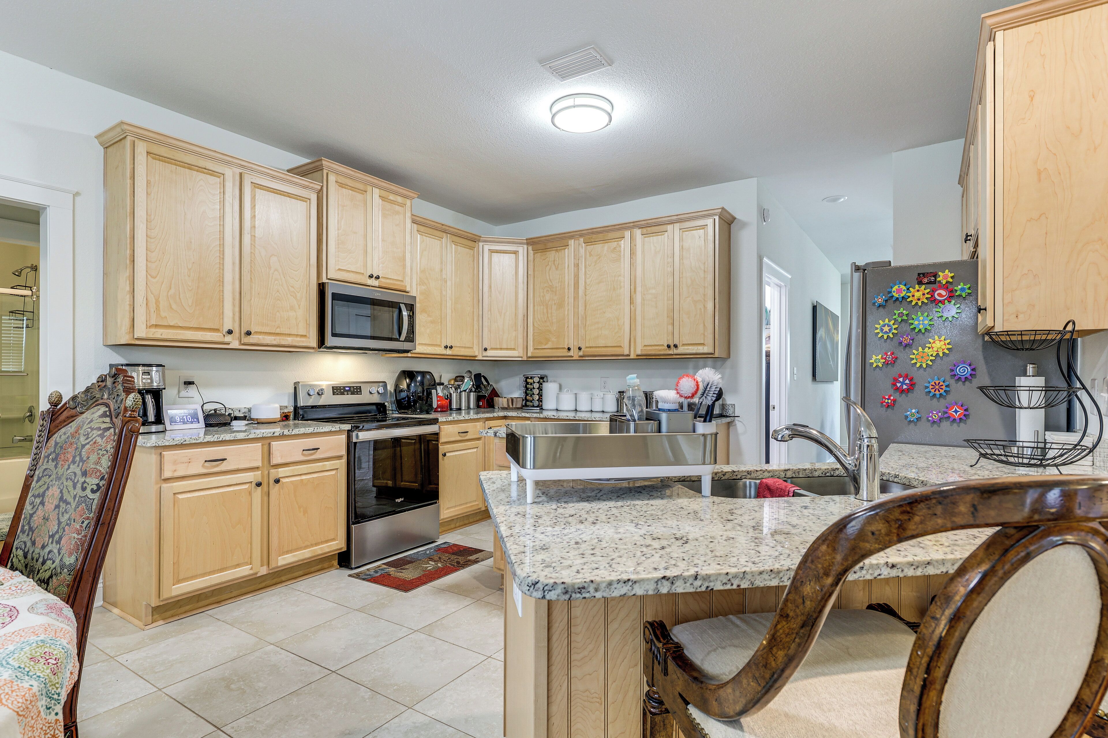 A kitchen with wooden cabinets, a stainless steel sink, and a microwave.