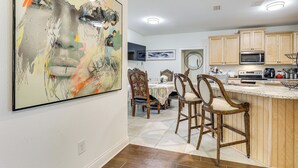 Une cuisine moderne avec des meubles en bois, un coin bar et un grand tableau abstrait accroché au mur.