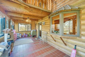 A log cabin with a kitchen area, a dining table, and a chair.