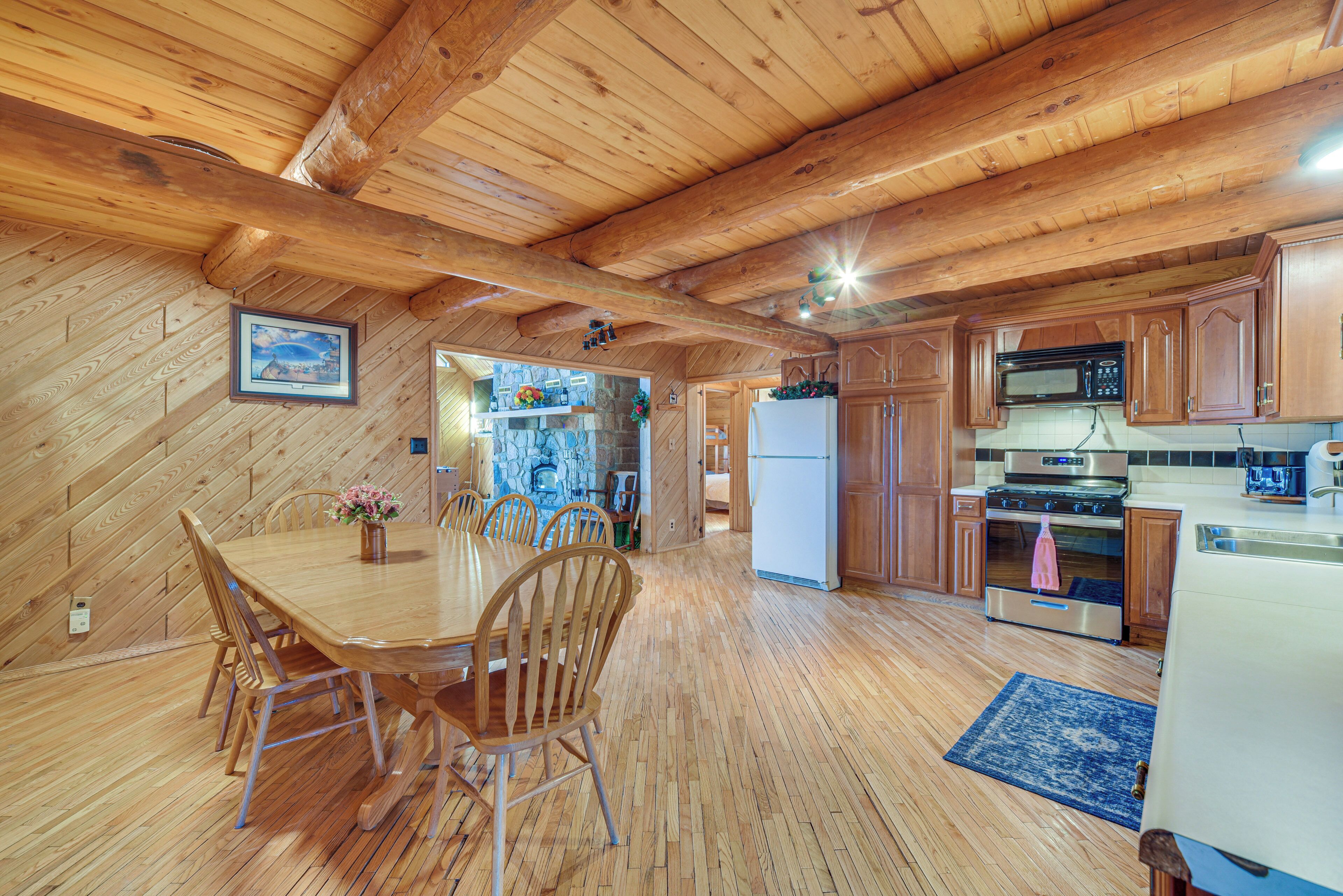 Un interior de madera con una mesa de comedor, sillas, armarios de madera, un refrigerador y un microondas.