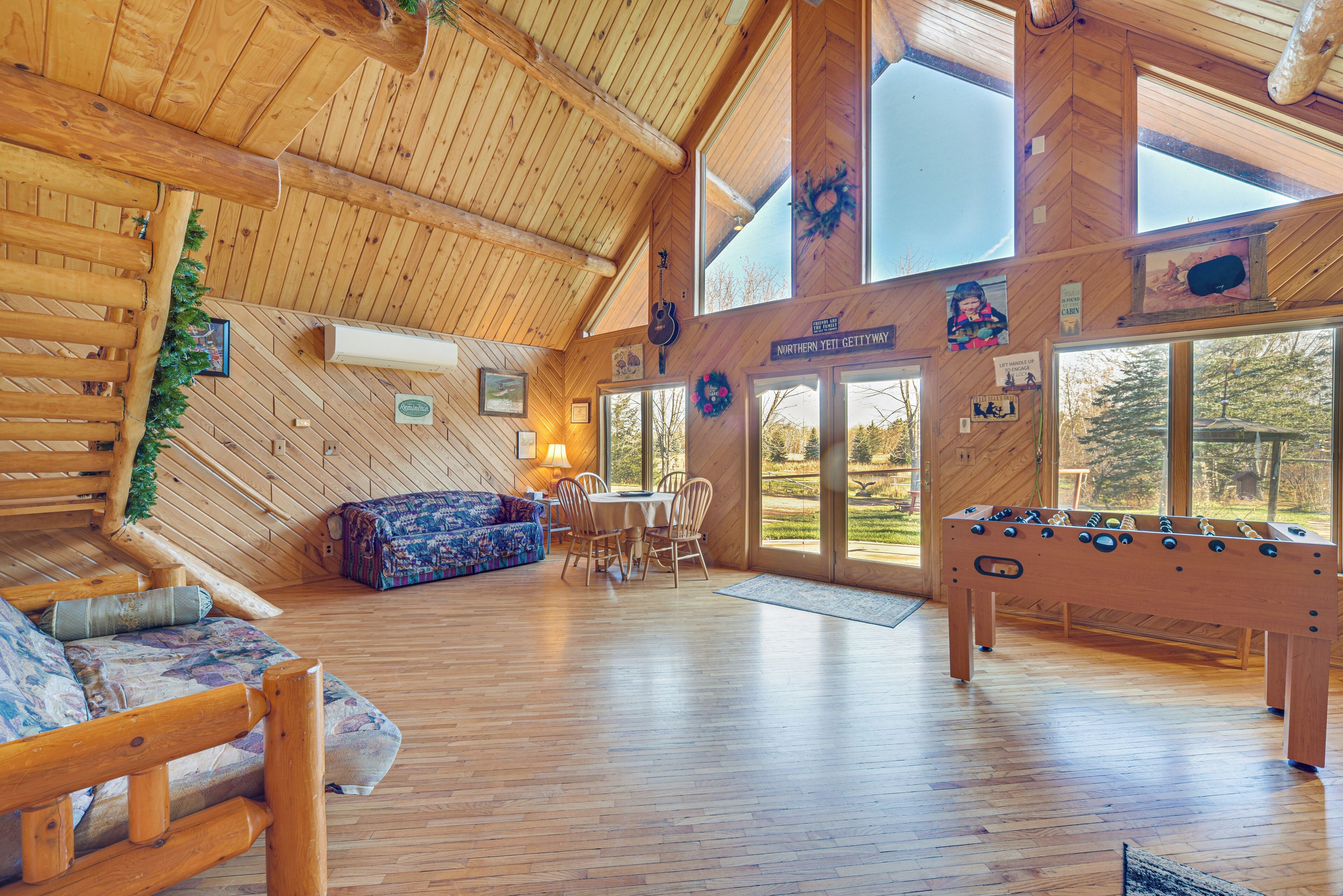Un intérieur spacieux en bois, comprenant un canapé, une table à manger et un baby-foot.