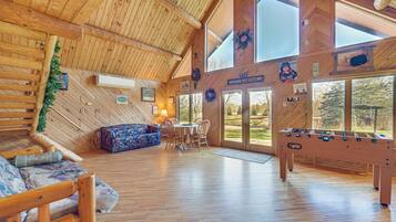 Un intérieur spacieux en bois, comprenant un canapé, une table à manger et un baby-foot.