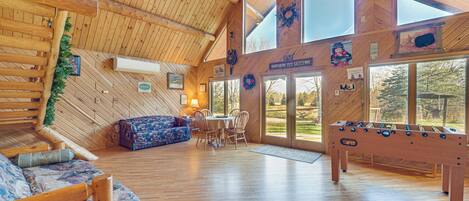 A spacious wooden interior with a sofa, dining table, and foosball table.