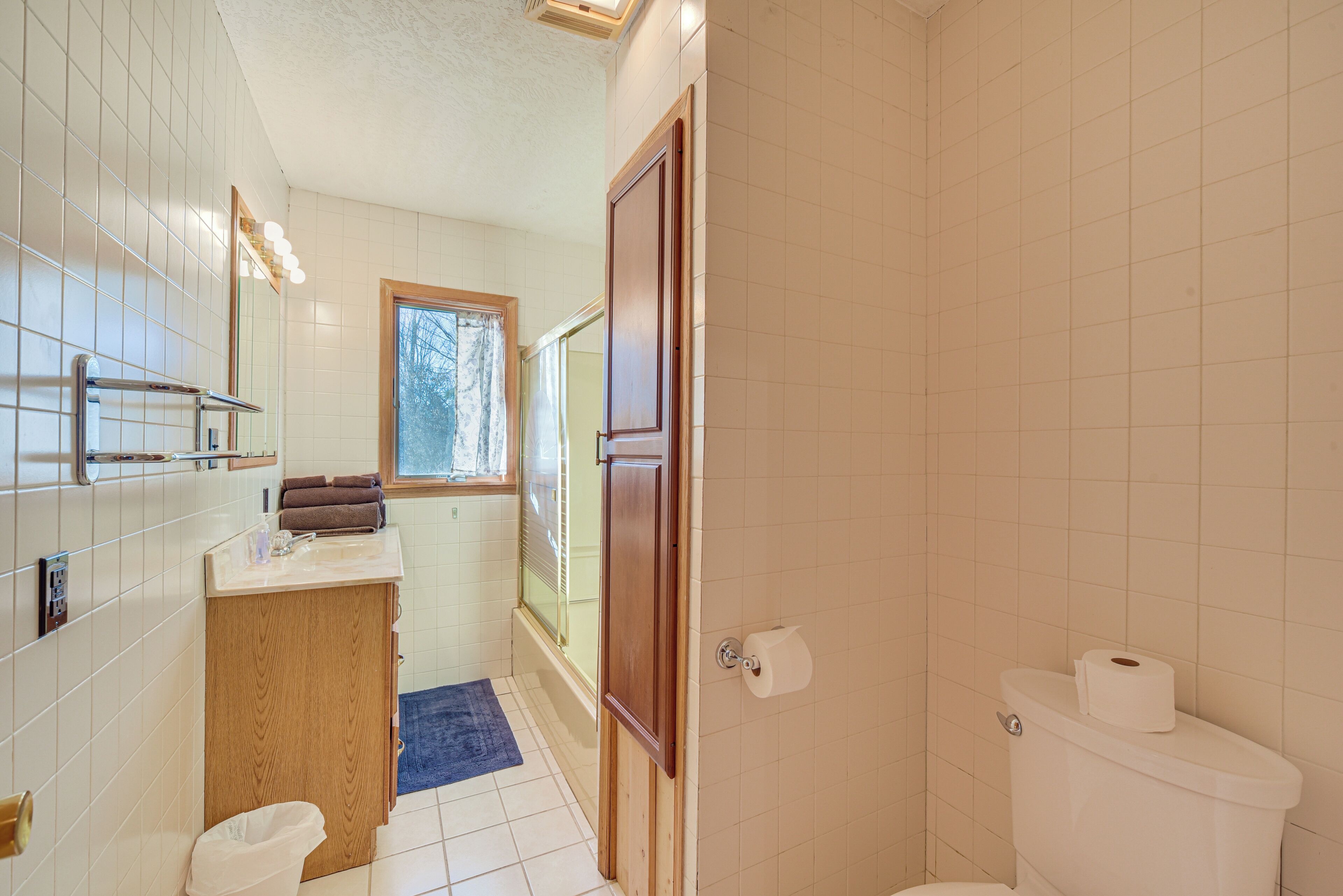 A bathroom with a toilet, a sink, a mirror, and a window.