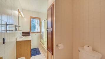 A bathroom with a toilet, a sink, a mirror, and a window.