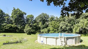 A circular above-ground pool with a ladder, surrounded by a grassy yard and trees. - Perfect Family Retreat: Pool, Fire Pit (Westfield)