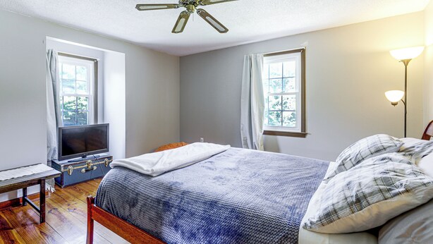A bedroom with a bed, a desk, a television, and a ceiling fan. - Perfect Family Retreat: Pool, Fire Pit (Westfield)