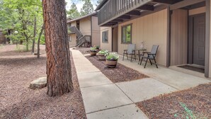 A building with a covered outdoor seating area, a staircase, and potted plants. - Great for Families! Pinetop Sanctuary w/ Patio (Pinetop)