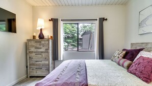 A bedroom with a bed, a dresser, a lamp, a window with curtains, and a view of the outside. - Great for Families! Pinetop Sanctuary w/ Patio (Pinetop)