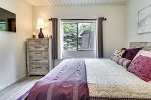 Un dormitorio con cama, cómoda, lámpara y ventana con cortinas.