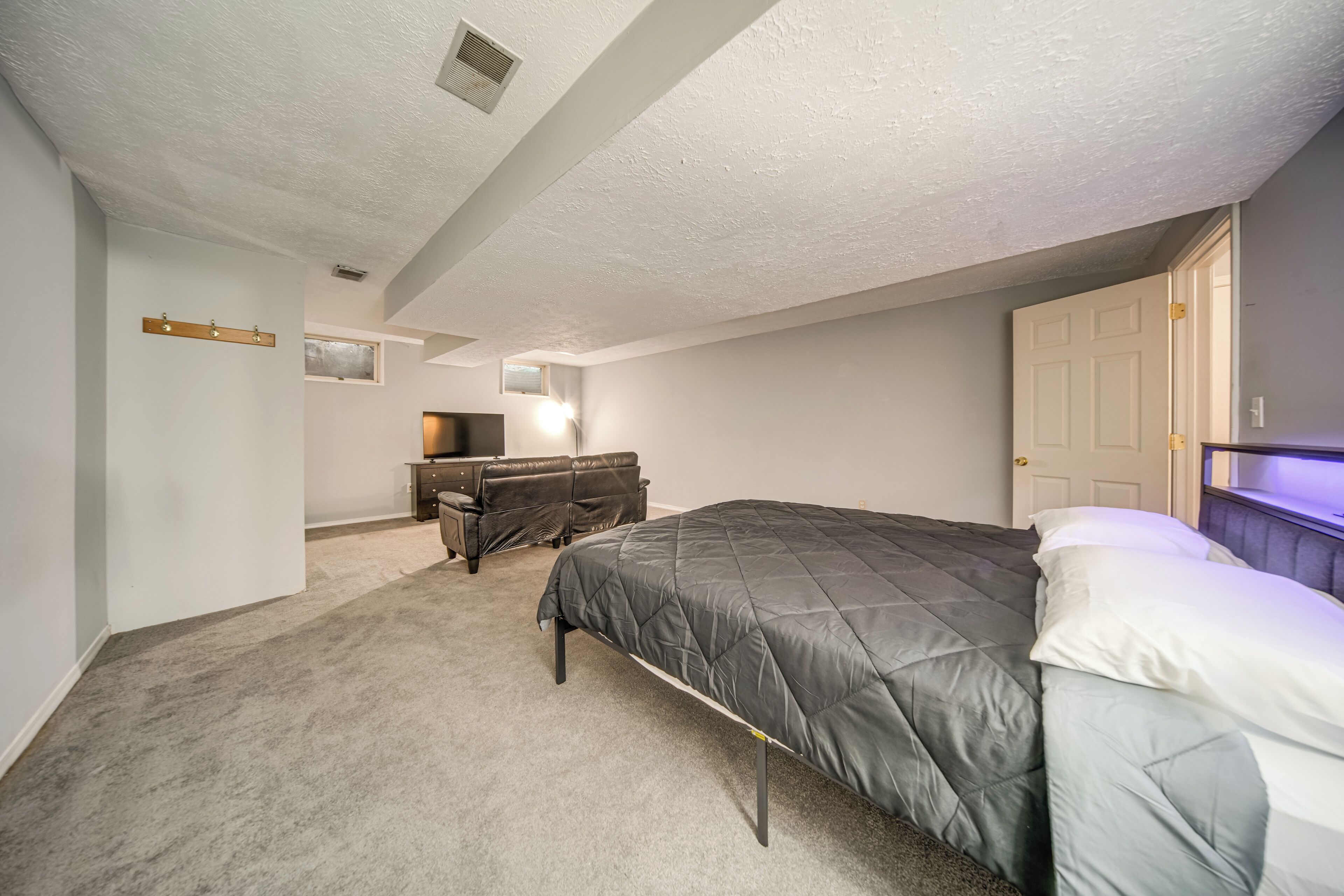 A bedroom with a bed, a desk, and a dresser.