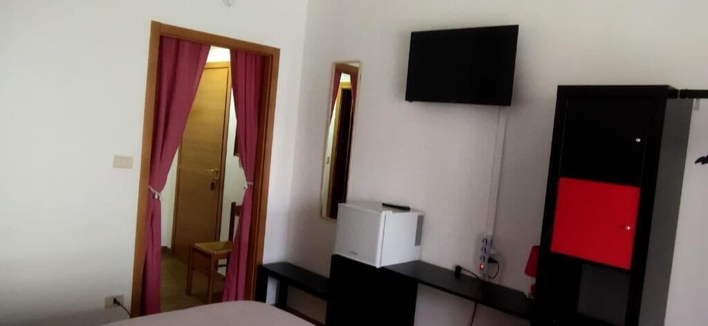 Ein Hotelzimmer mit Bett, Schreibtisch, Stuhl, Fernseher und Kleiderschrank.