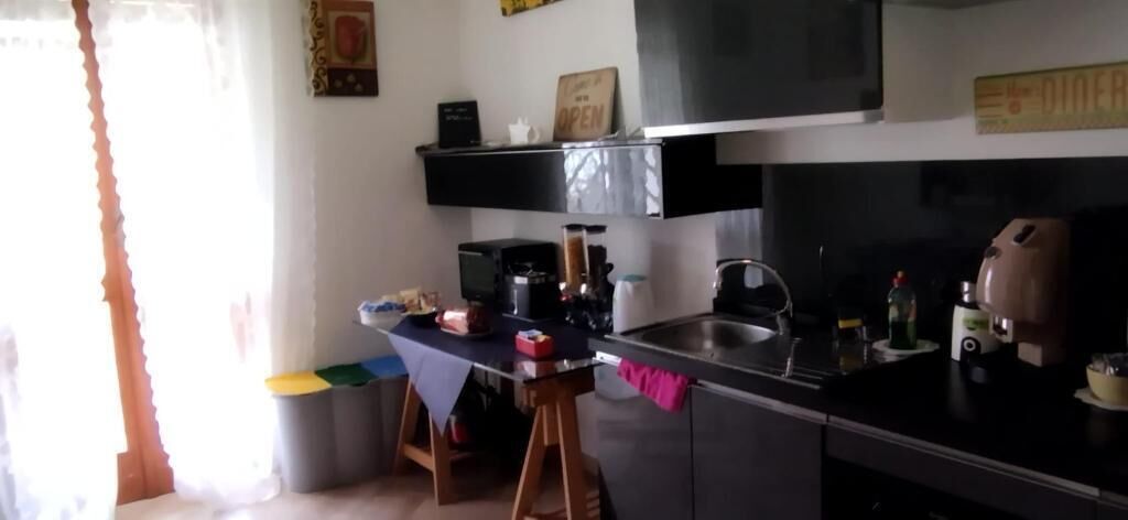 A kitchen with a black countertop, a wooden stool, and a table with a blue tablecloth.