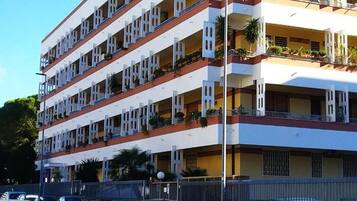 Un hotel a più piani con balconi, tetto piano e perimetro recintato.