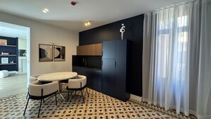A modern kitchen with a dining area, featuring a patterned floor, a black cabinet, and a white ceiling light.