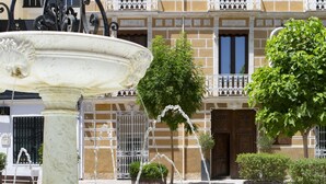A courtyard with a fountain, a building with balconies, and potted plants.
