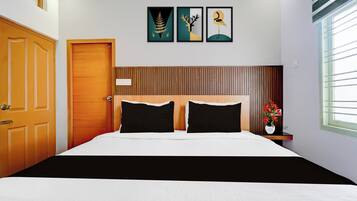A bedroom with a wooden door, a bed with black and white bedding, and a window with blinds.