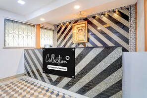 A reception desk with a sign indicating company service, a patterned wall, and a check-in/out sign.