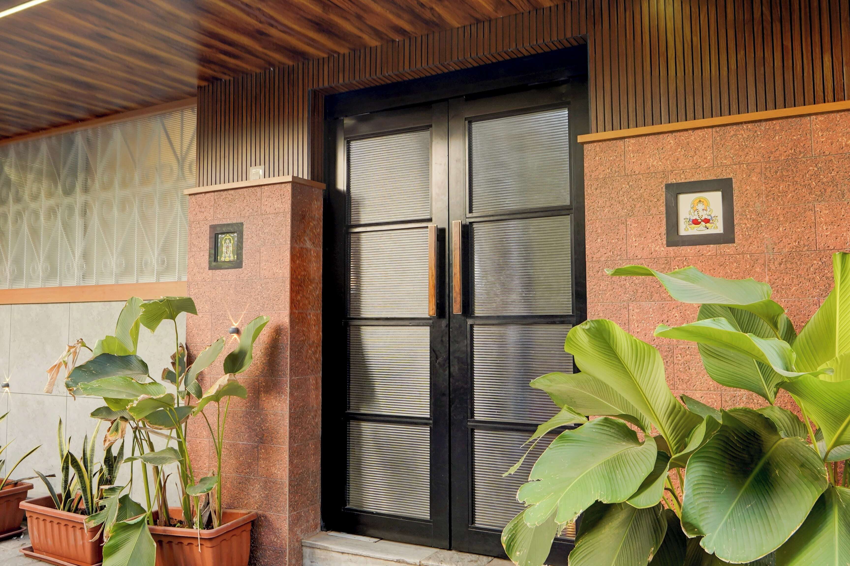 A hotel entrance with a wooden ceiling, a closed metal door, and potted plants.
