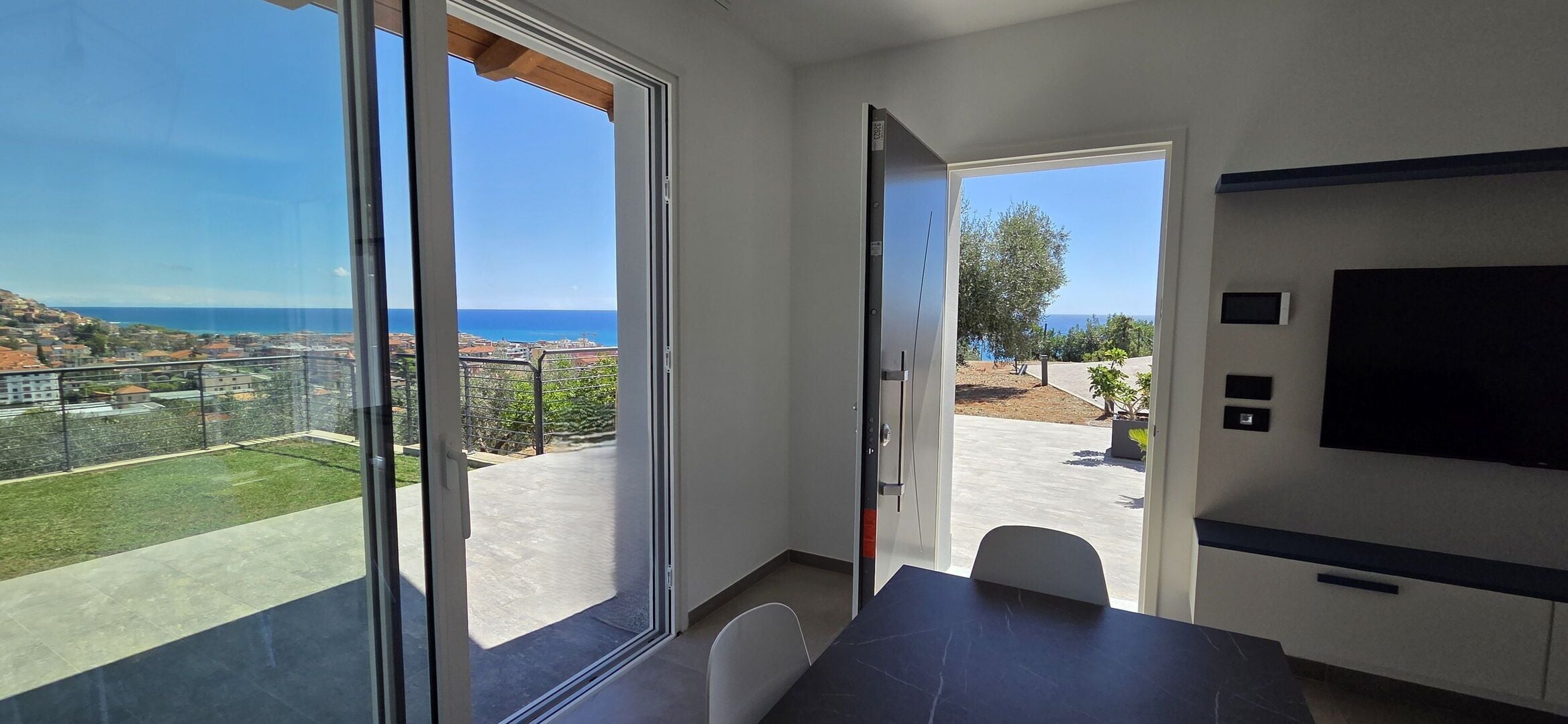 A modern room with large sliding glass doors leading to a balcony with a sea view.