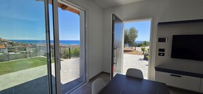 Una habitación moderna con grandes puertas corredizas de vidrio que dan a un balcón con vista al mar.